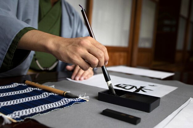 Homem praticando caligrafia japonesa com uma variedade de ferramentas