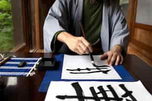 Foto grátis homem praticando caligrafia japonesa com uma variedade de ferramentas