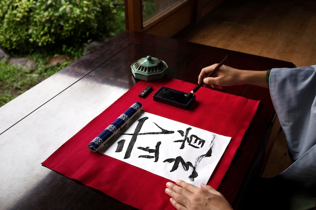 Homem praticando caligrafia japonesa com uma variedade de ferramentas