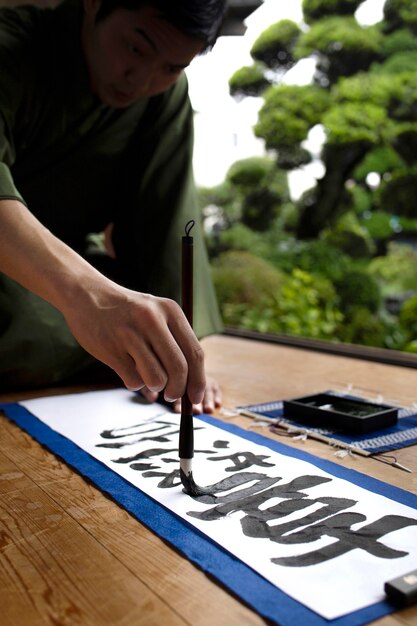 Homem praticando caligrafia japonesa com uma variedade de ferramentas