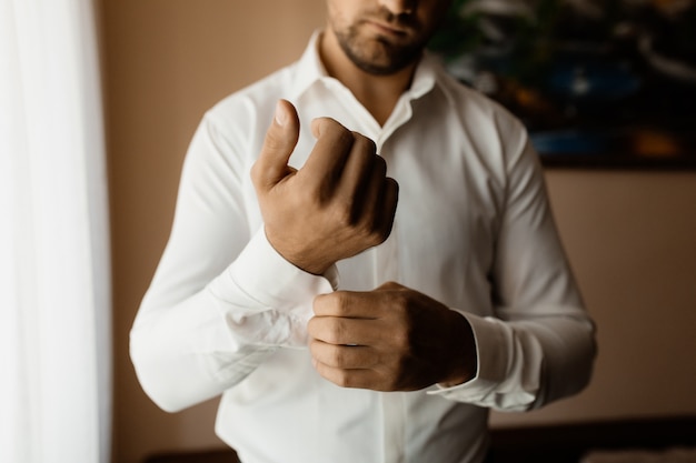 Homem prende um botão na manga da camisa