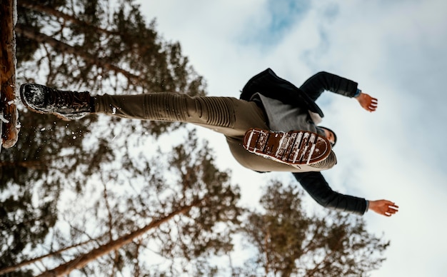 Foto grátis homem pulando ao ar livre na natureza durante o inverno