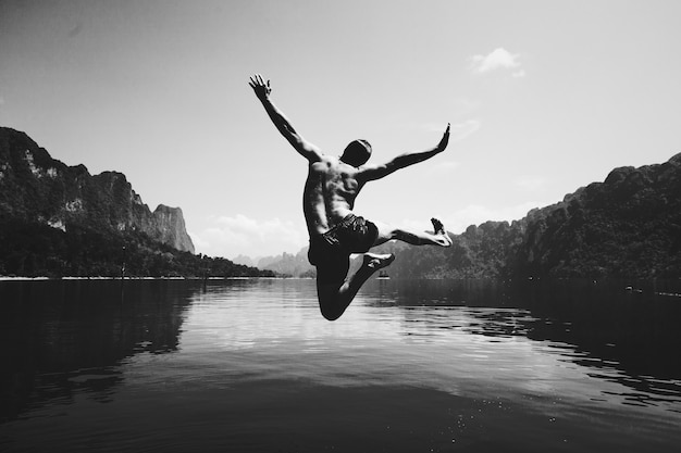 Homem pulando de alegria à beira de um lago