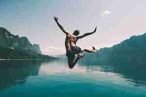 Foto grátis homem pulando de alegria por um lago