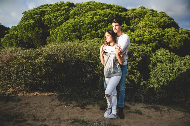 Homem que abraça mulher por trás com uma floresta com árvores atrás