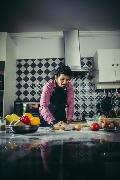 Homem que amassa a massa caseiro da pizza na cozinha. Conceito de cozinha.