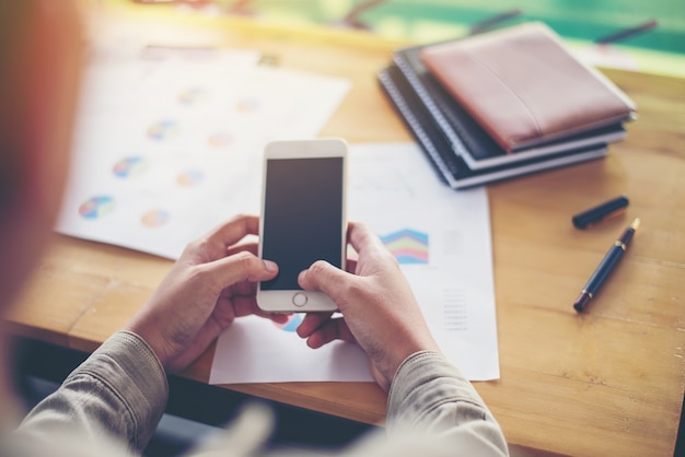 Homem que datilografa em seu telefone em uma mesa