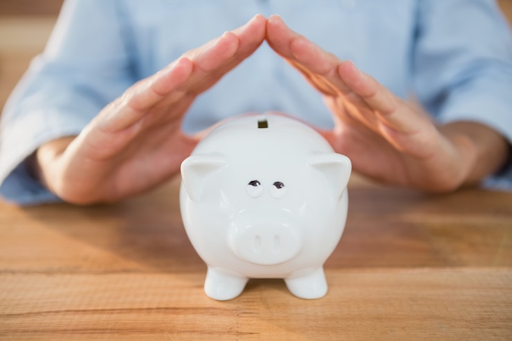 Foto grátis homem que faz um gesto do telhado no banco piggy