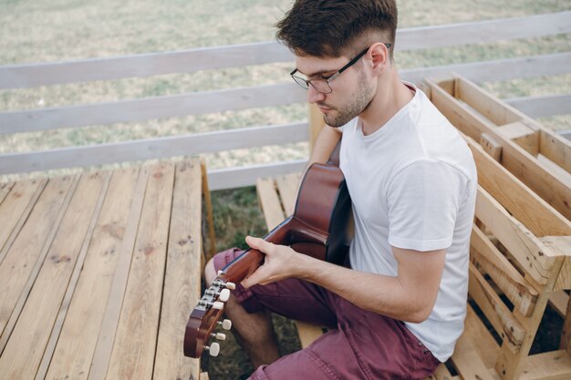 Homem que joga a guitarra em mesas de madeira com vidros para ver