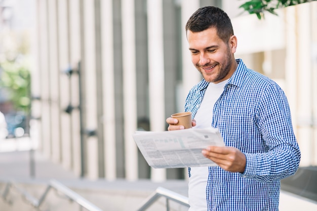 Homem que lê um jornal perto do prédio