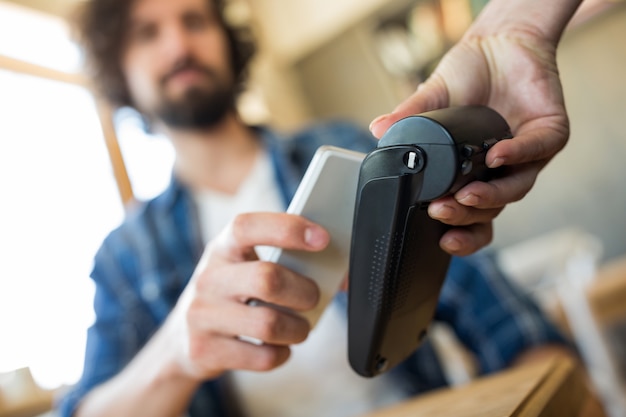 Homem que paga com a tecnologia NFC no telefone móvel