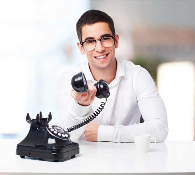 Homem que sorri com um telefone antigo na mão