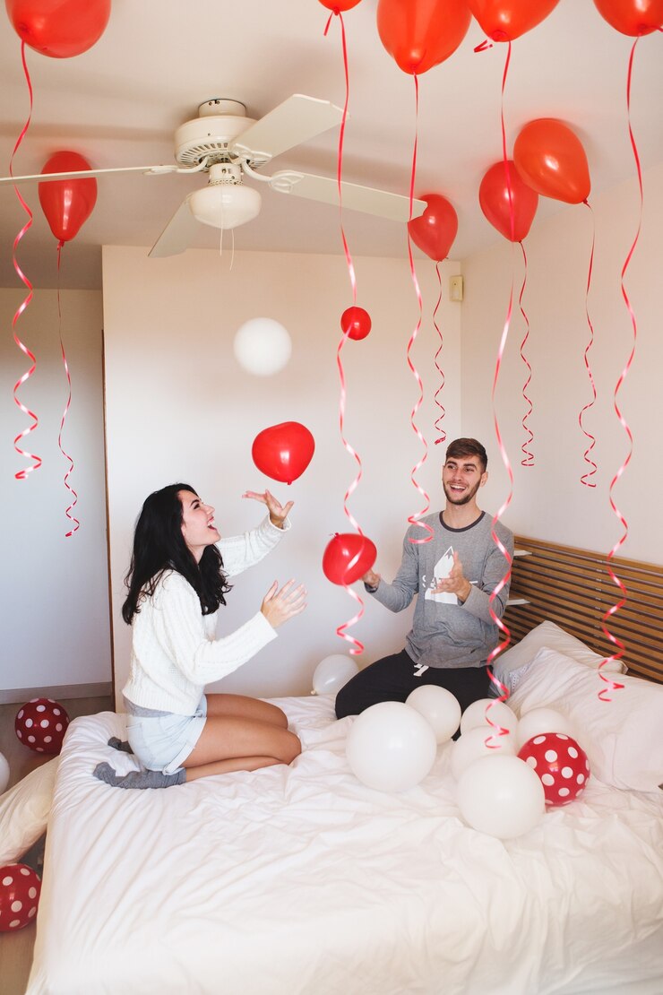 Foto grátis homem que sorri quando sua amiga olha para a sala cheia de balões vermelhos