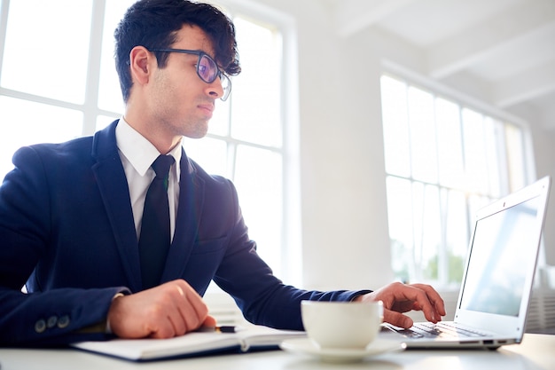 Homem que trabalha com o laptop no escritório