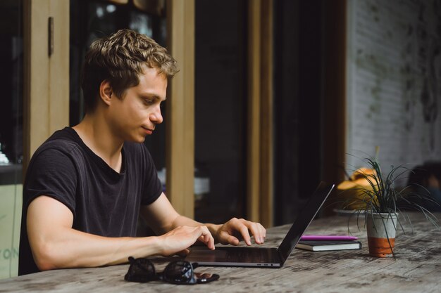 homem que trabalha com um laptop em um café em uma mesa de madeira