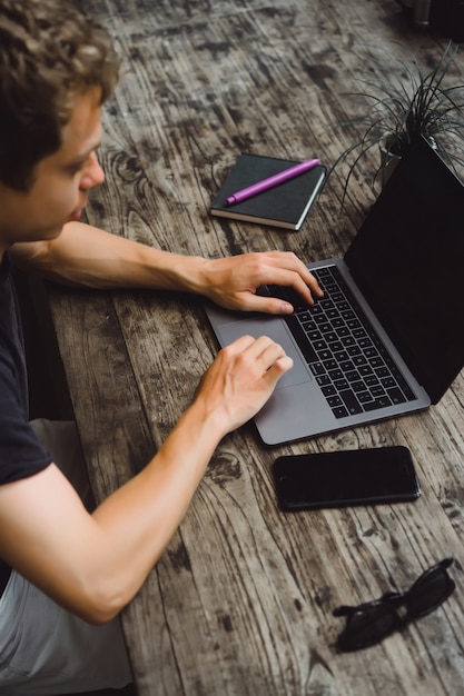 Foto grátis homem que trabalha com um laptop em um café em uma mesa de madeira