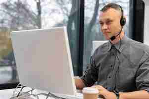 Foto grátis homem que trabalha em um call center com fones de ouvido e computador