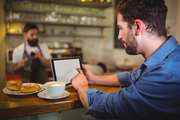 Homem que usa a tabuleta digital ao ter café no cafÃ ©