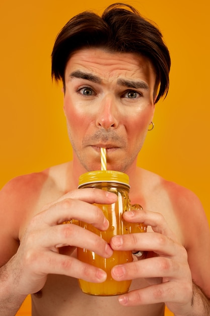 Foto grátis homem queimado de sol vista frontal posando com bebida