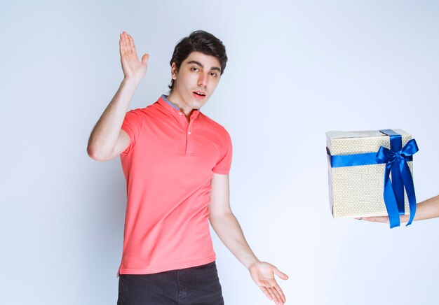 Homem recebendo e segurando uma caixa de presente branca embrulhada com fita azul com as duas mãos