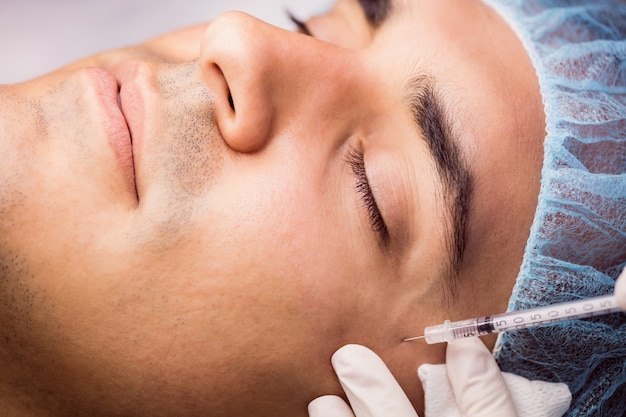 Homem recebendo injeção de botox no rosto