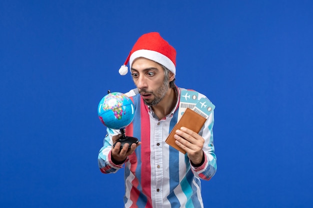 Homem regular de vista frontal com ingressos e globo na mesa azul emoção feriado ano novo