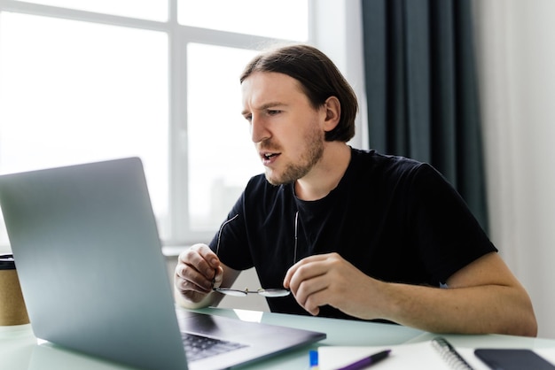 Homem relaxado trabalhando no escritório contemporâneo digitando no teclado sentado na cadeira confortável