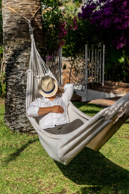 Homem relaxando em uma rede no jardim.