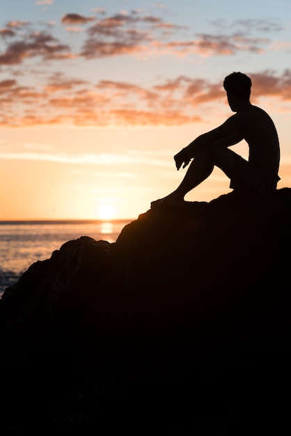 Homem, relaxante, praia, em, pôr do sol