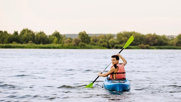 Homem, remo, kayaking, sobre, lago, olhando para trás