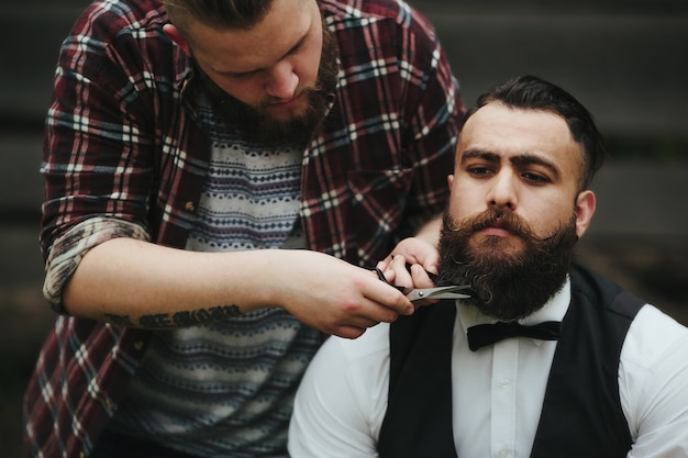 Homem retocar a barba de seu amigo