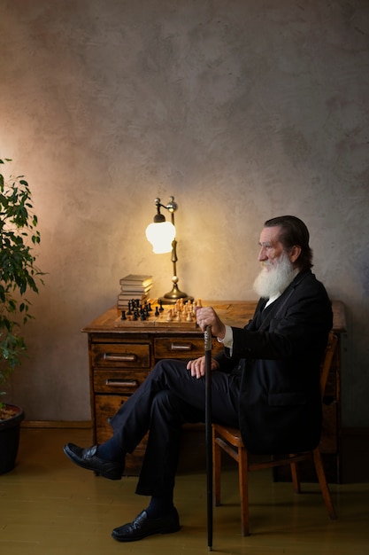 Foto grátis homem sábio com barba sentado na cadeira com bengala