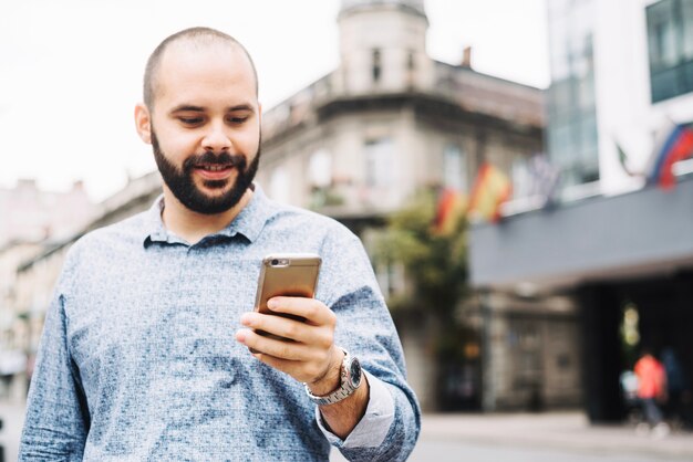 Homem satisfeito assistindo telefone na rua