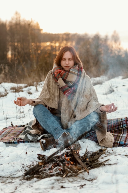 Foto grátis homem se aquecendo ao lado de uma fogueira no inverno