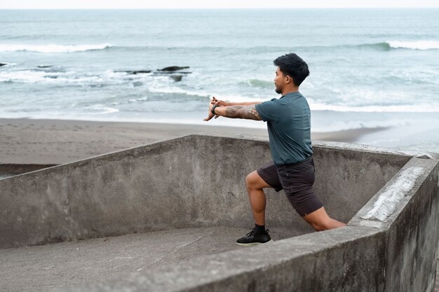 Homem se espreguiçando na vista lateral da praia