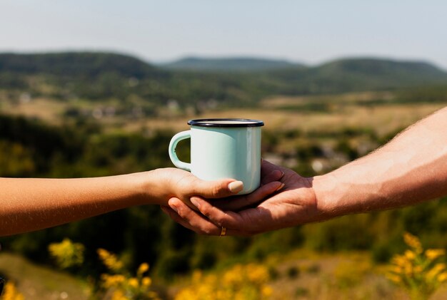 Homem segurando a mão de uma mulher e uma xícara de café