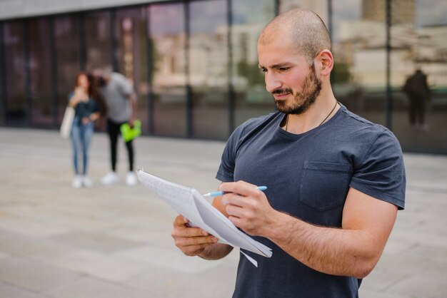 Homem segurando caderno apontando com caneta