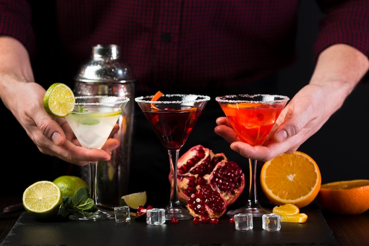 Foto grátis homem segurando copos de cocktail coloridos