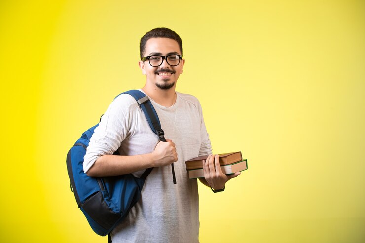 Foto grátis homem segurando dois livros, olhando direto e sorrindo.