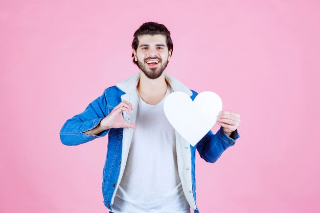 Homem segurando e apresentando uma figura de coração em branco com sorrisos