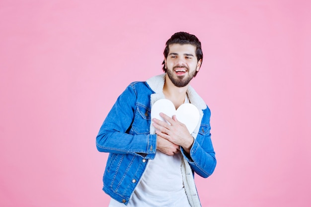 Homem segurando e apresentando uma figura de coração em branco com sorrisos