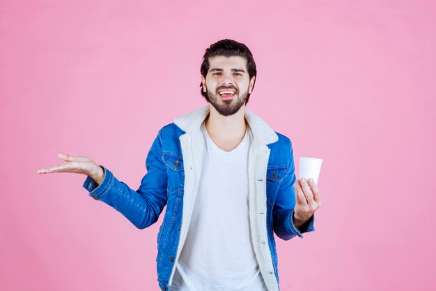 Homem segurando e apresentando uma nova xícara de café descartável