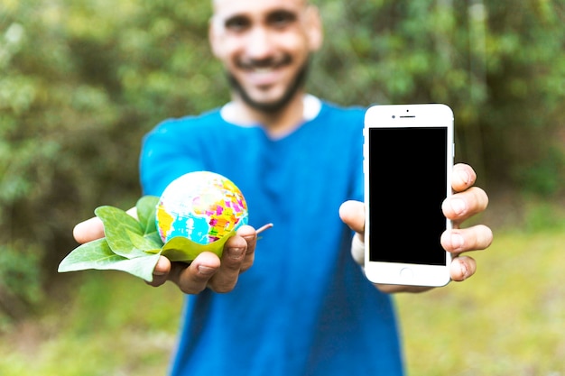 Foto grátis homem, segurando, globo, com, folha, e, smartphone