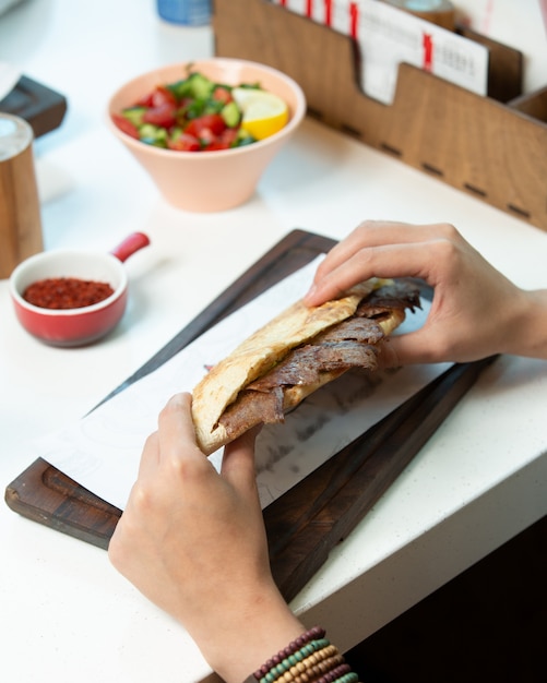 Foto grátis homem segurando kebab de carne no pão no café