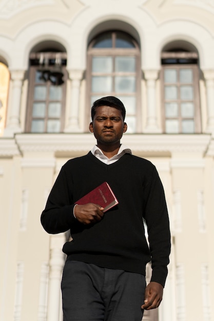 Foto grátis homem segurando livro bíblico fora da igreja