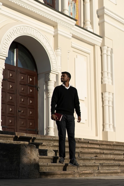 Foto grátis homem segurando livro bíblico fora da igreja