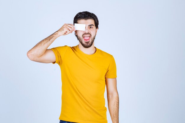 Homem segurando seu cartão de visita aos olhos.