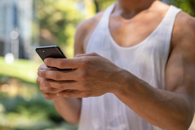 Homem segurando smartphone ao ar livre enquanto faz exercícios