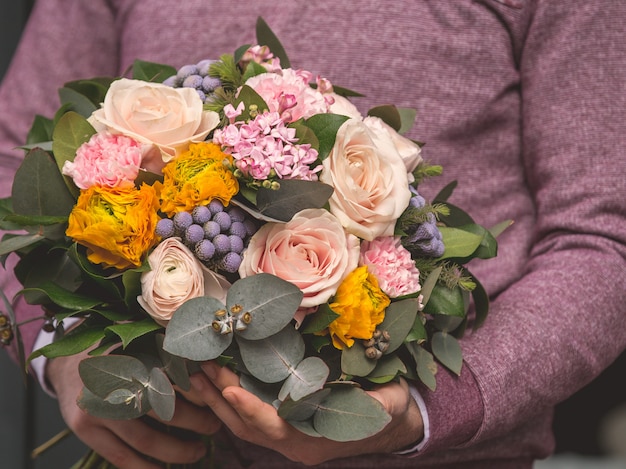 Foto grátis homem segurando um buquê romântico de flores de seleção mista e pronto para oferecer