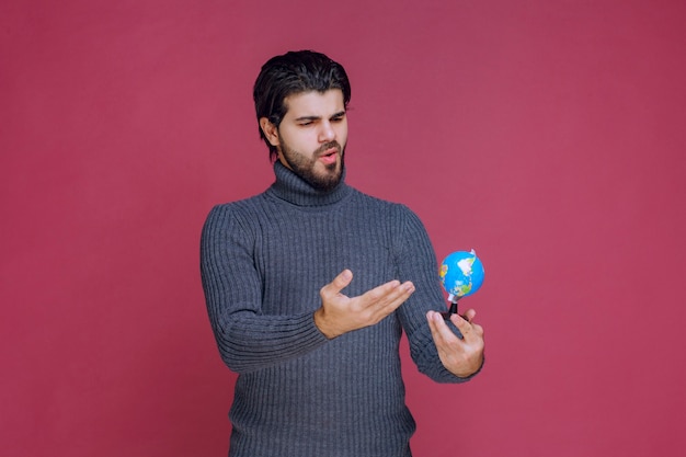 Homem segurando um mini globo e fazendo uma apresentação sobre ele.